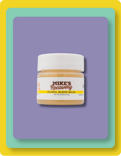 A small jar of Mike's Recovery Floral Blend Balm with a white lid and white label, centered on a purple rounded rectangle with a yellow and mint border.