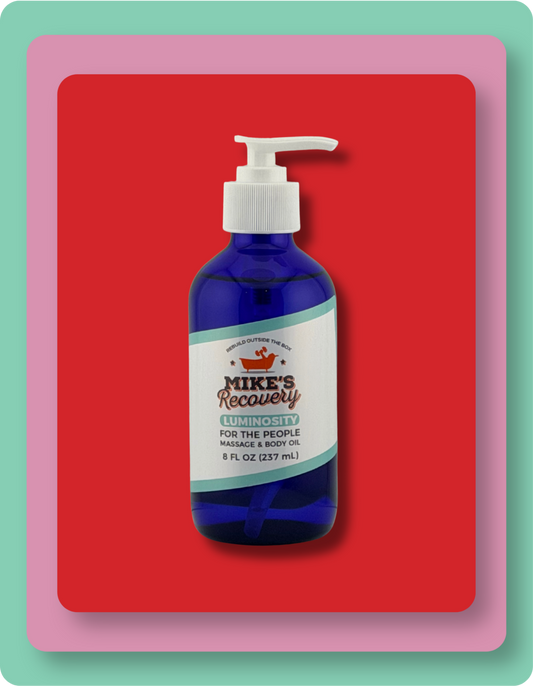A blue pump bottle of Mike's Recovery Luminosity Aromatherapy massage and body oil centered on a red background with layered pink and mint green border frames.