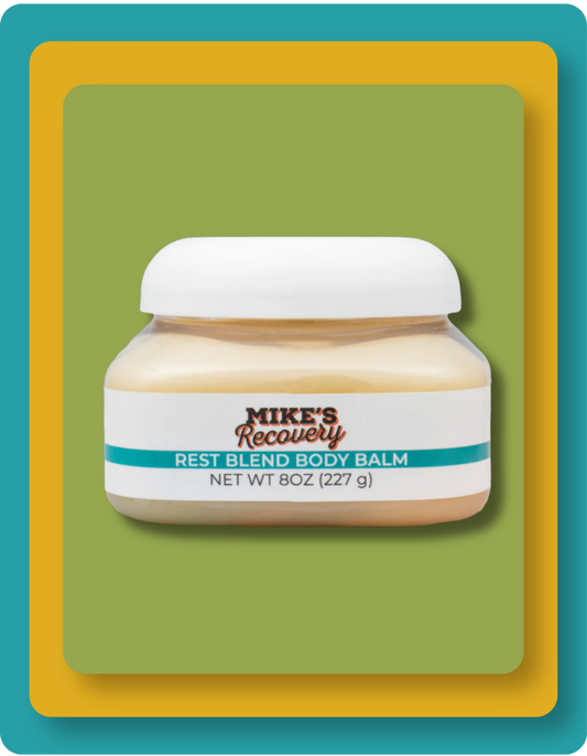 A jar of Mike's Recovery Rest Blend Body Balm with a white cap and white label, set against a green and yellow graphic background.