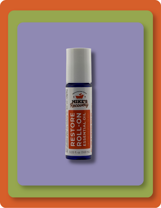 A small essential oil roll-on bottle labeled 'Mike's Recovery Restore Roll-On Essential Oil' centered on a lavender rectangle, with a green and orange border around the image.